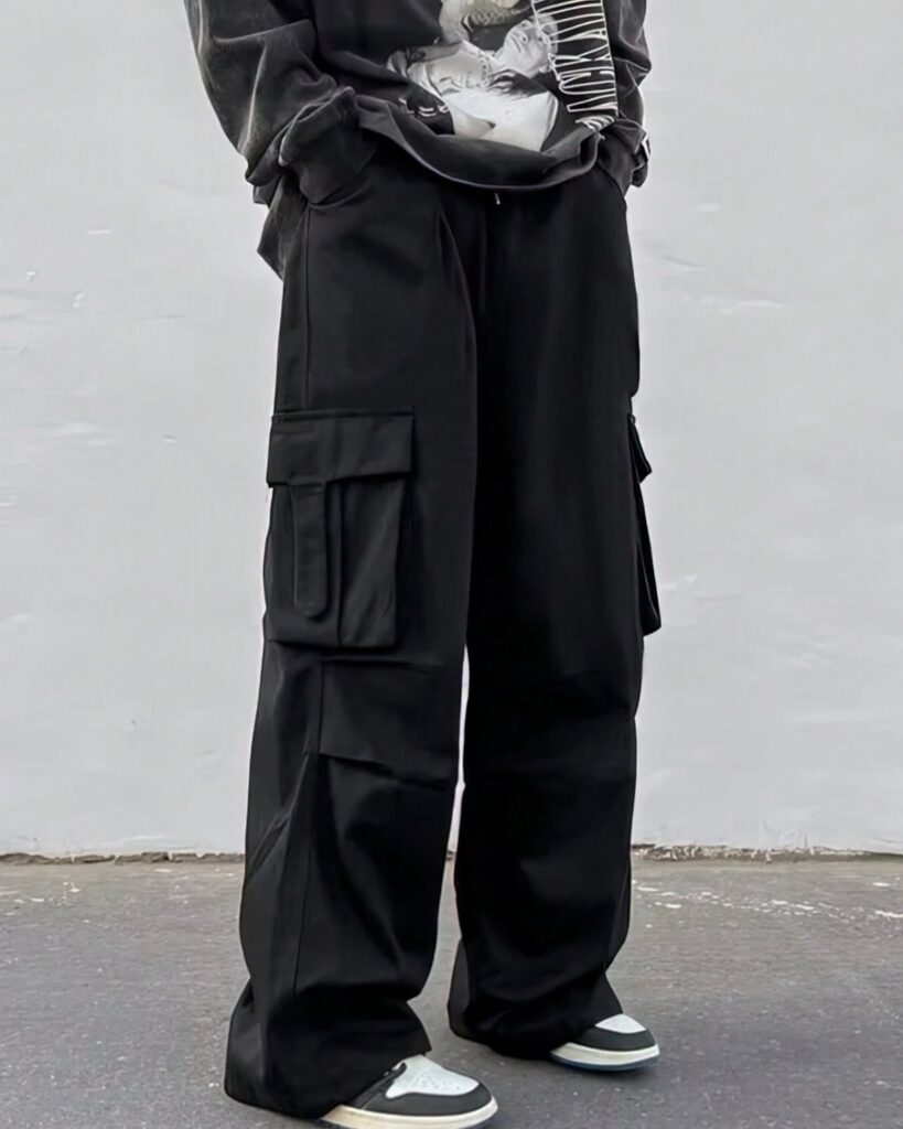 Man wearing baggy black cargo pants, a grey graphic tee, and sneakers.