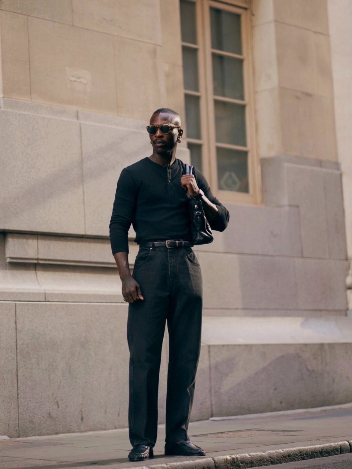 Man in black henley and dark grey trousers wearing black dress shoes.