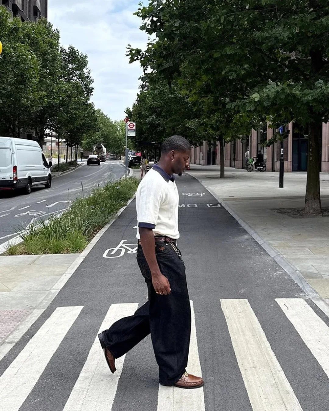 Man in white polo and navy trousers wearing brown leather shoes crossing street