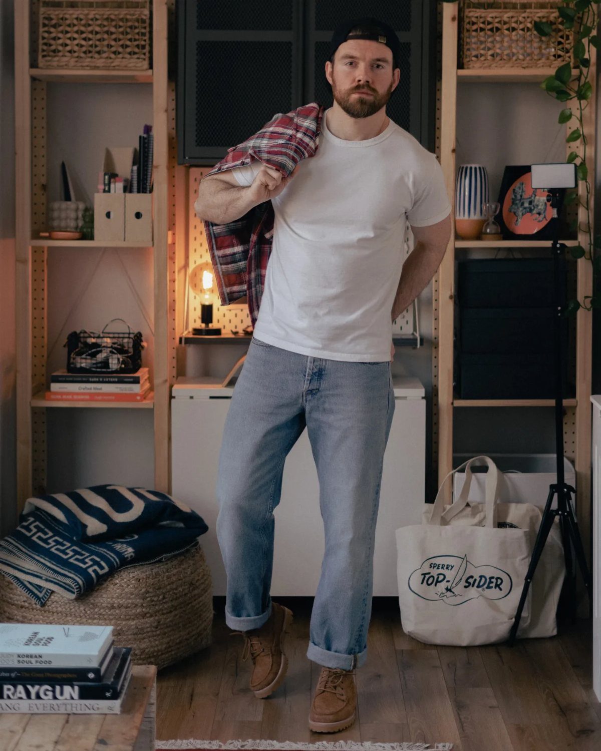 Man wearing white t-shirt, cuffed jeans, and brown suede chukka boots indoors.