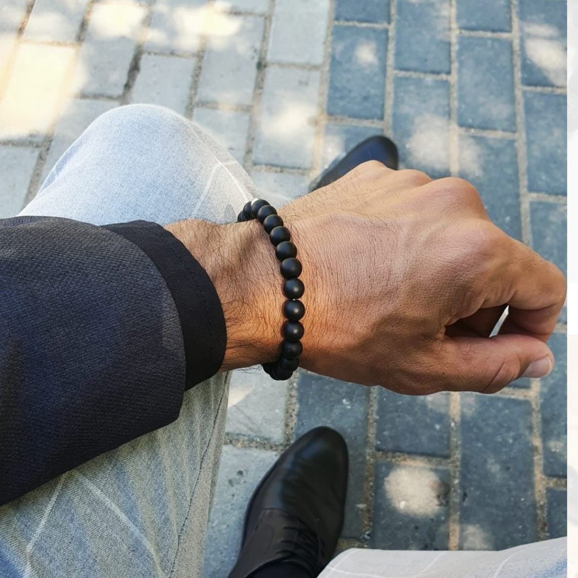 Matte black bead bracelet on a man's wrist wearing a blue blazer.