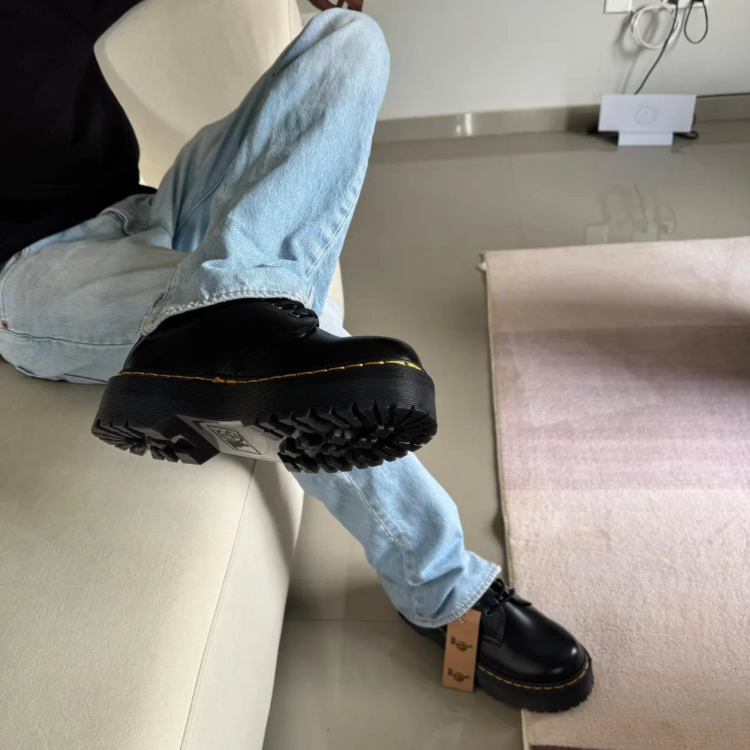 Light blue jeans and black leather combat boots on a person sitting.