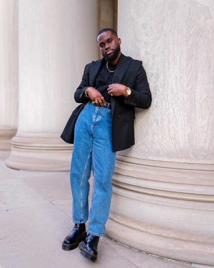 Man wearing a black blazer, light blue jeans, and black Dr. Martens boots.