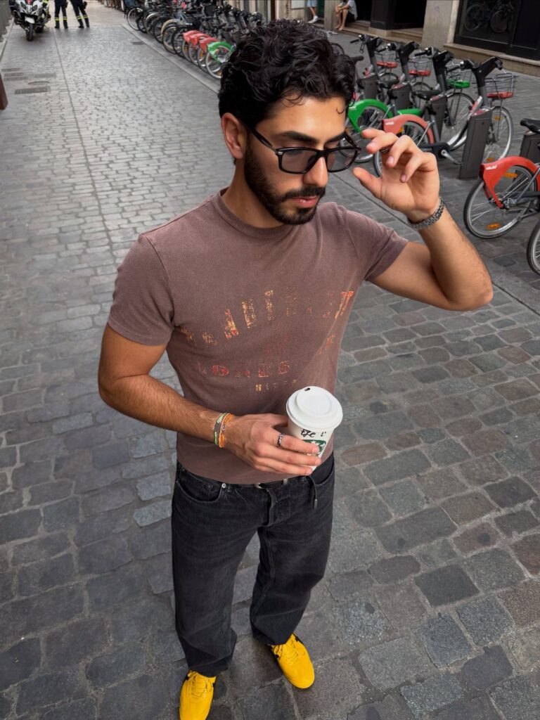 Man in brown t-shirt and dark jeans wearing bright yellow sneakers on street