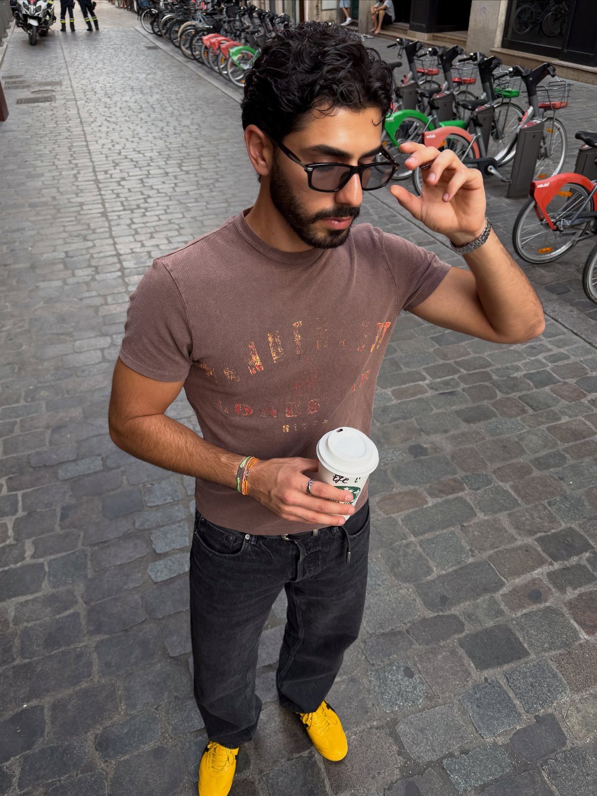 Man in brown t-shirt and dark jeans wearing bright yellow sneakers on street