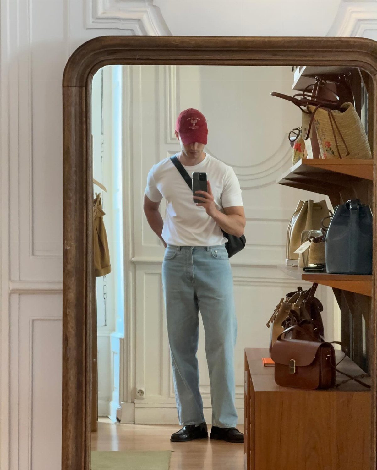 Man in white t-shirt and light blue jeans wearing black penny loafers.