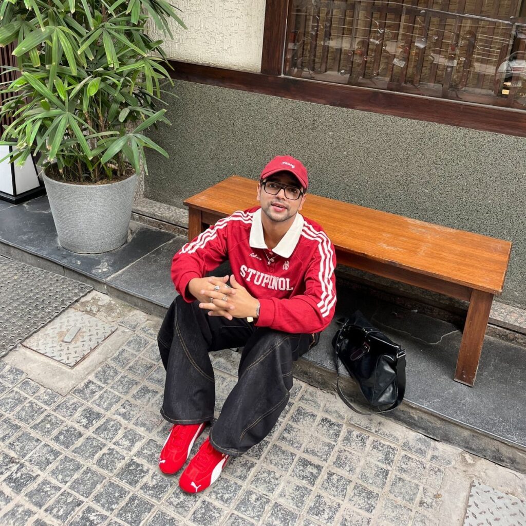 Man in red jacket and cap wearing bright red sneakers sitting on bench