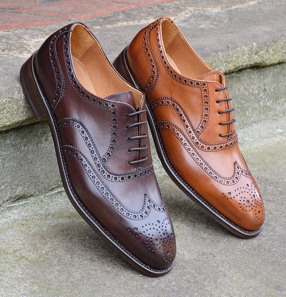 Dark brown and tan leather brogue shoes resting on a stone step.