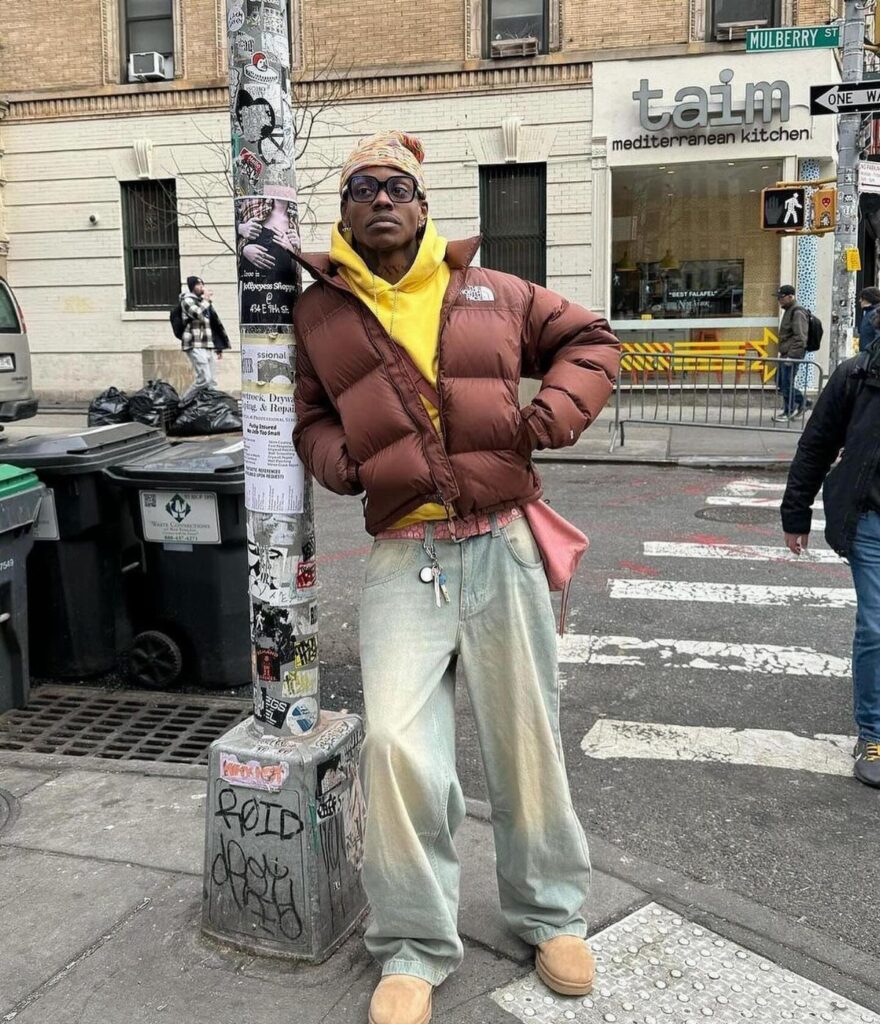 Person in brown puffer jacket and tan Ugg boots posing on city street