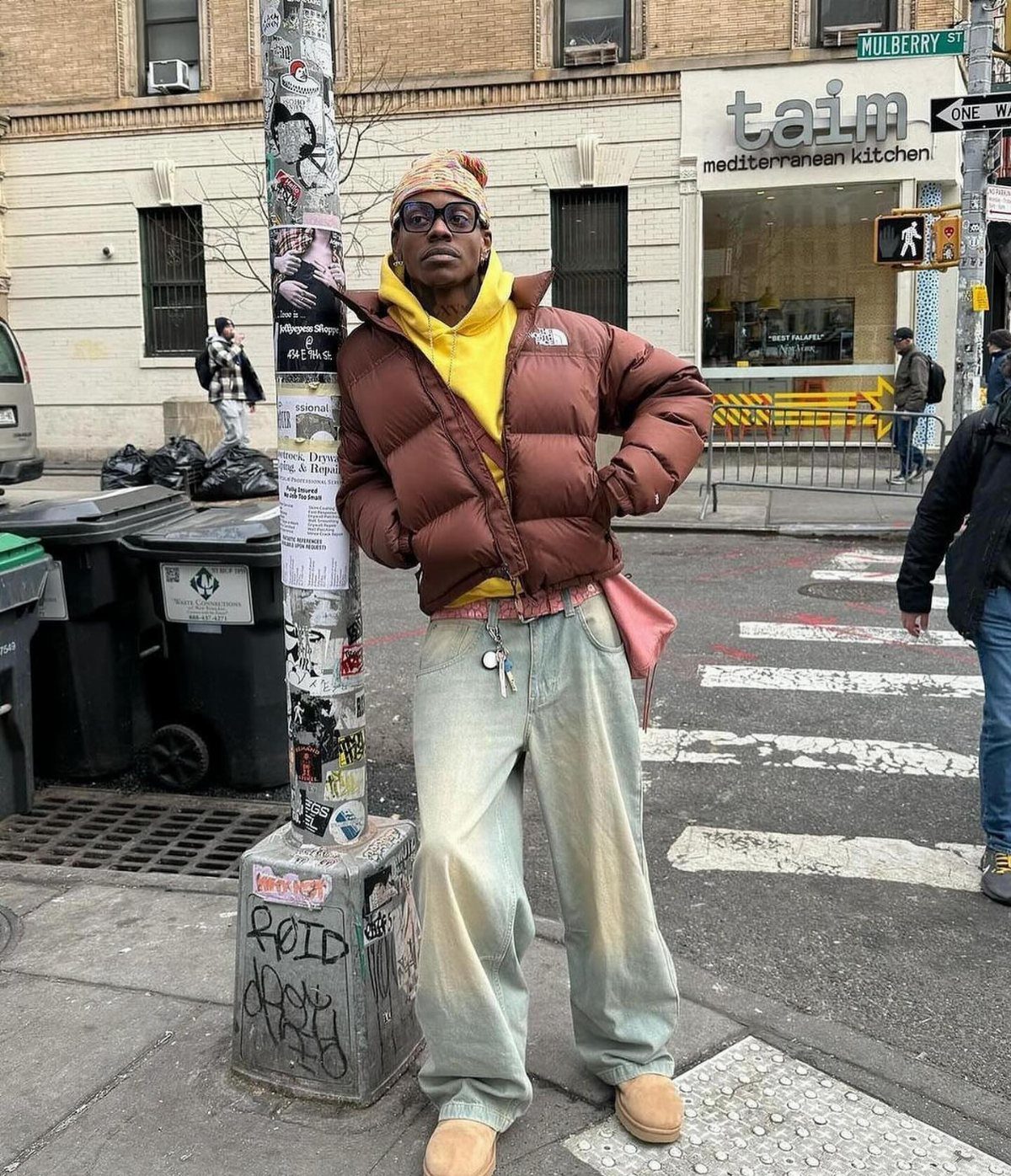 Person in brown puffer jacket and tan Ugg boots posing on city street