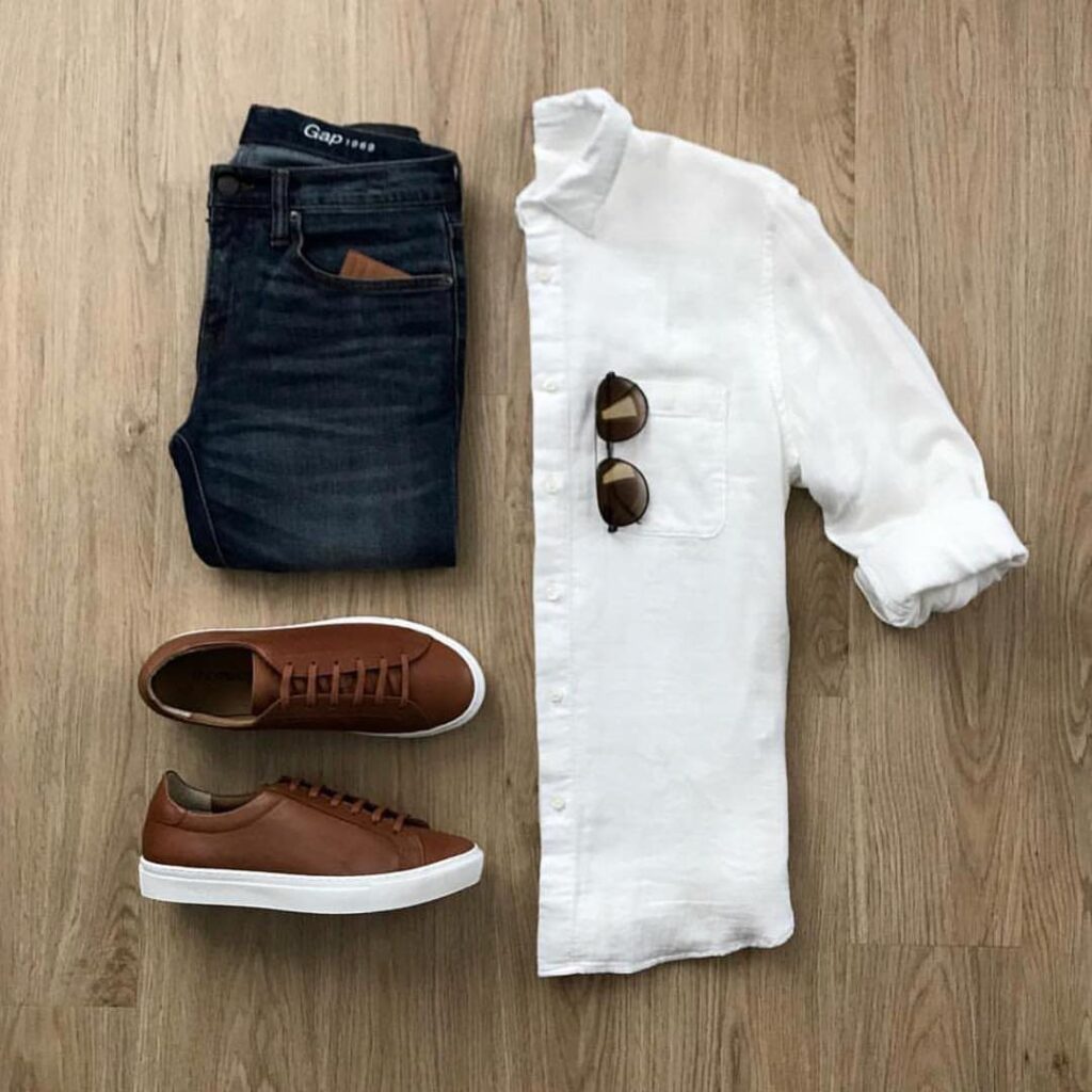 Brown leather sneakers paired with dark blue jeans and a white button-down shirt.
